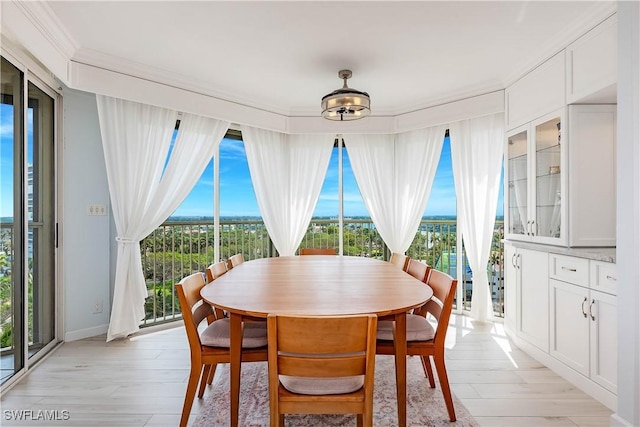 dining space featuring light wood-style floors and ornamental molding