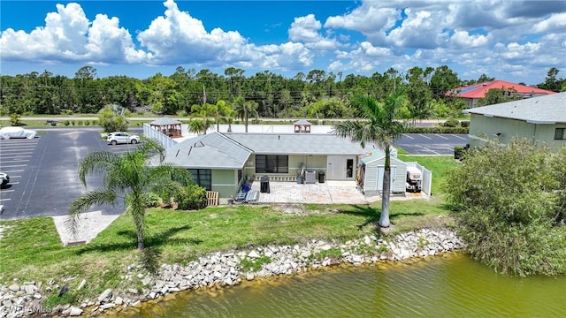 back of house featuring a yard, a water view, and a patio area