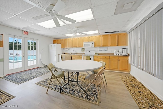 dining room with a paneled ceiling, a ceiling fan, light wood-style flooring, and french doors