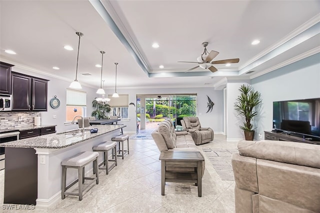 12740 Seaside Key Ct, North Fort Myers, FL 33903 - living room with ceiling fan, recessed lighting, a tray ceiling, ornamental molding, and light tile patterned floors