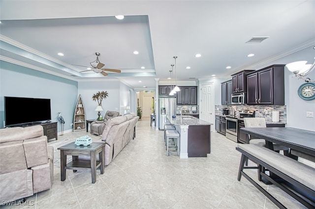 12740 Seaside Key Ct, North Fort Myers, FL 33903 - living room with crown molding, a ceiling fan, recessed lighting, a tray ceiling, and a chandelier