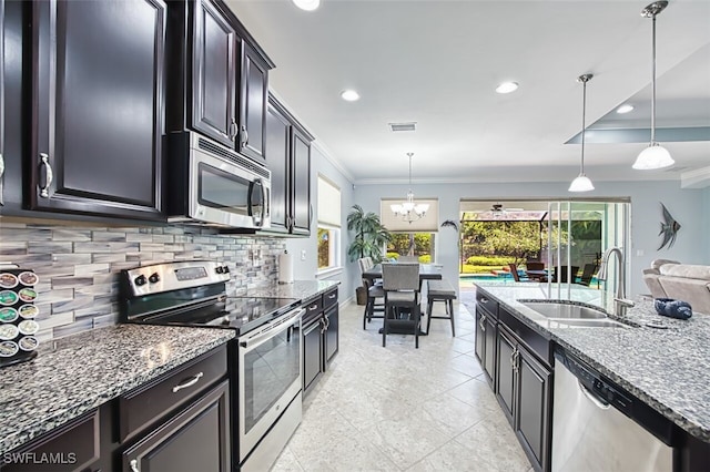 12740 Seaside Key Ct, North Fort Myers, FL 33903 - kitchen featuring appliances with stainless steel finishes, crown molding, decorative backsplash, dark stone countertops, and hanging light fixtures