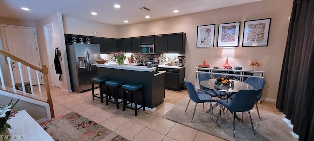 3268 Aralia Ct E, Alva, FL 33920 - kitchen with stainless steel appliances, dark cabinetry, a center island, light countertops, and decorative backsplash