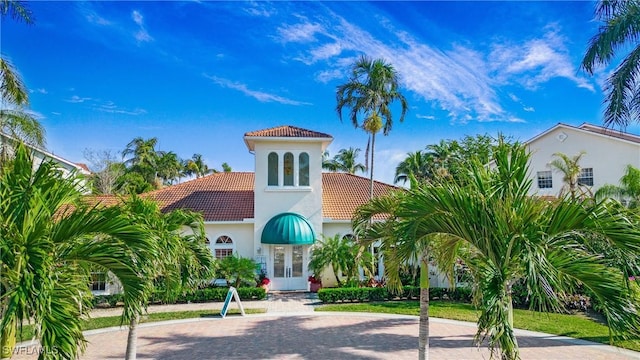 mediterranean / spanish home with french doors, stucco siding, and a tile roof