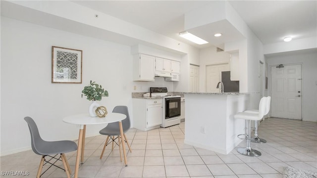 kitchen with a kitchen breakfast bar, white cabinets, white range with electric cooktop, refrigerator, and a peninsula