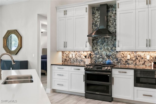 641 Diplomat Ct, Marco Island, FL 34145 - kitchen with white cabinets, wall chimney exhaust hood, decorative backsplash, range with two ovens, and a sink