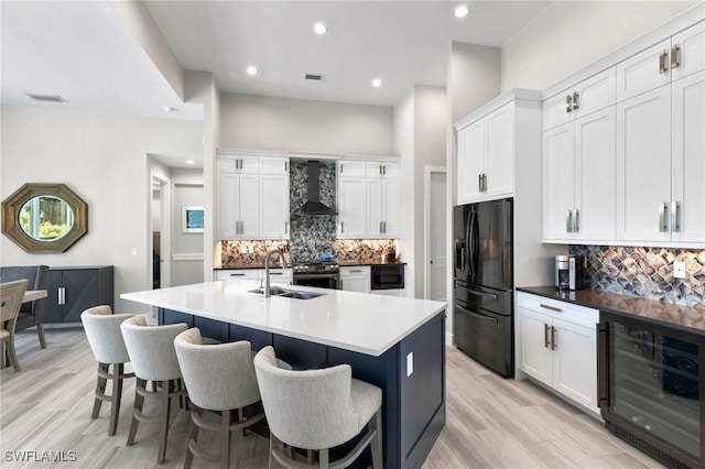 641 Diplomat Ct, Marco Island, FL 34145 - kitchen with black refrigerator with ice dispenser, wall chimney exhaust hood, a kitchen bar, wine cooler, and a sink