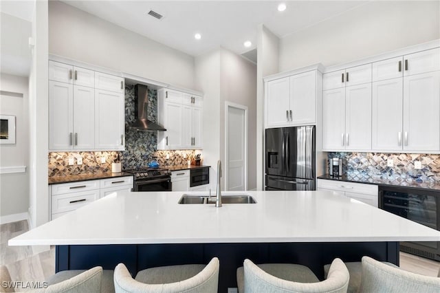 641 Diplomat Ct, Marco Island, FL 34145 - kitchen with wall chimney range hood, gas range, a sink, stainless steel fridge, and wine cooler
