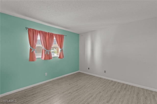 spare room featuring baseboards, wood finished floors, and a textured ceiling
