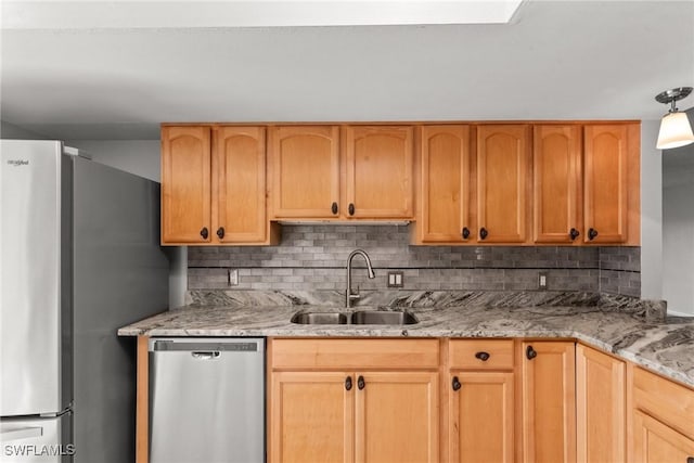 kitchen with light stone countertops, appliances with stainless steel finishes, decorative backsplash, and a sink