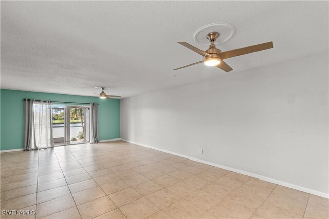 unfurnished room with baseboards, a ceiling fan, a textured ceiling, and light tile patterned floors