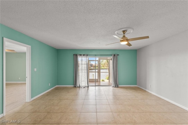 spare room featuring a textured ceiling, baseboards, ceiling fan, and light tile patterned floors