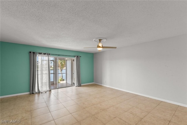 tiled spare room with ceiling fan, baseboards, and a textured ceiling