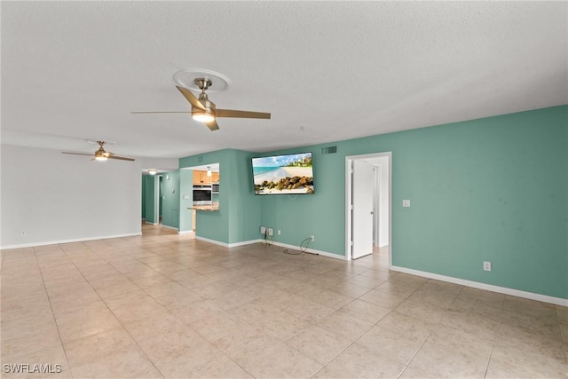 unfurnished room with light tile patterned floors, baseboards, a textured ceiling, and ceiling fan