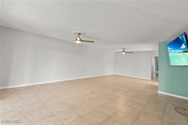 spare room featuring baseboards, a ceiling fan, and a textured ceiling