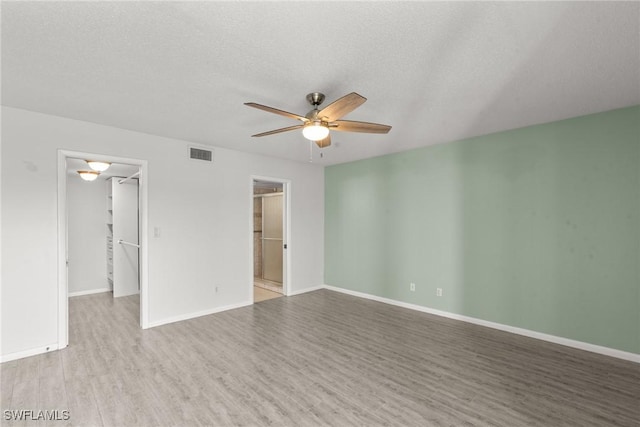 unfurnished room with baseboards, a ceiling fan, wood finished floors, and visible vents