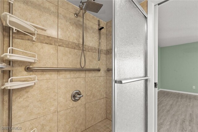 bathroom featuring baseboards, wood finished floors, and a stall shower