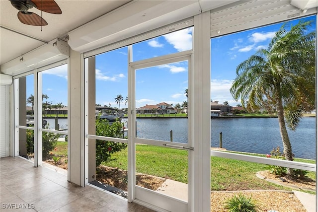 unfurnished sunroom with a water view, a ceiling fan, and a healthy amount of sunlight