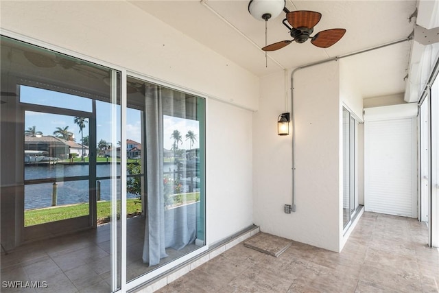 unfurnished sunroom featuring ceiling fan and a water view