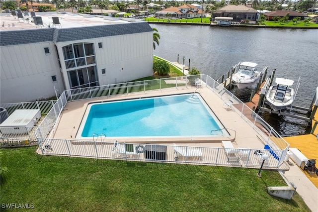 community pool with a yard, a water view, and fence
