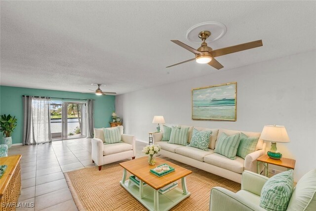 living room with a textured ceiling, tile patterned flooring, baseboards, and ceiling fan
