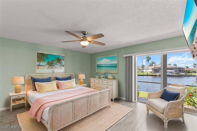 bedroom with light wood-type flooring, baseboards, and a textured ceiling