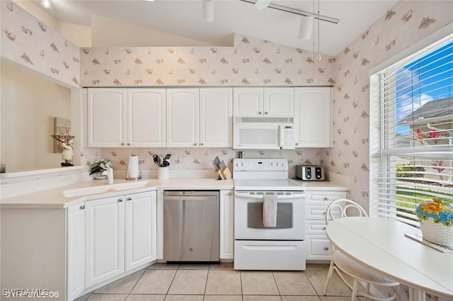 20902 Blacksmith Frg, Estero, FL 33928 - kitchen featuring white appliances, wallpapered walls, lofted ceiling, white cabinets, and light tile patterned floors