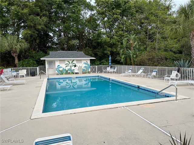 pool featuring an outdoor structure, fence, and a patio