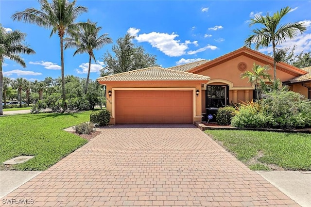 9190 Water Tupelo Rd, Fort Myers, FL 33912 - mediterranean / spanish house featuring a front lawn, a tile roof, a garage, stucco siding, and decorative driveway