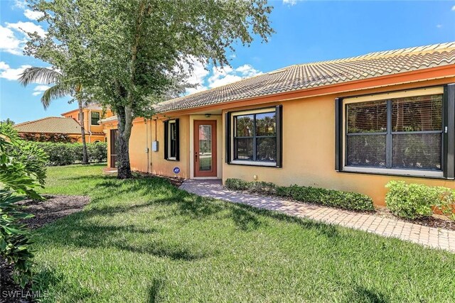 9190 Water Tupelo Rd, Fort Myers, FL 33912 - exterior space with a front lawn, stucco siding, and a tile roof