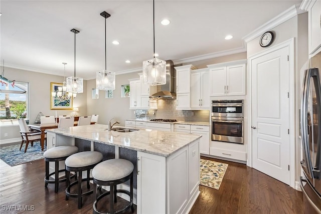 kitchen with crown molding, wall chimney exhaust hood, decorative backsplash, stainless steel appliances, and a sink