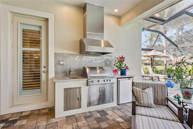 kitchen with a sink, wall chimney range hood, backsplash, and refrigerator