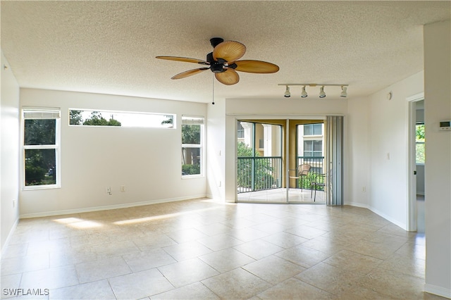 spare room featuring track lighting, a textured ceiling, baseboards, and ceiling fan