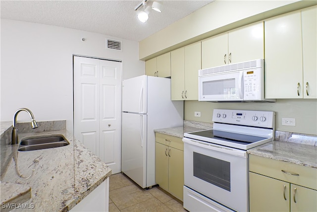 kitchen with white appliances, a textured ceiling, light tile patterned flooring, visible vents, and a sink