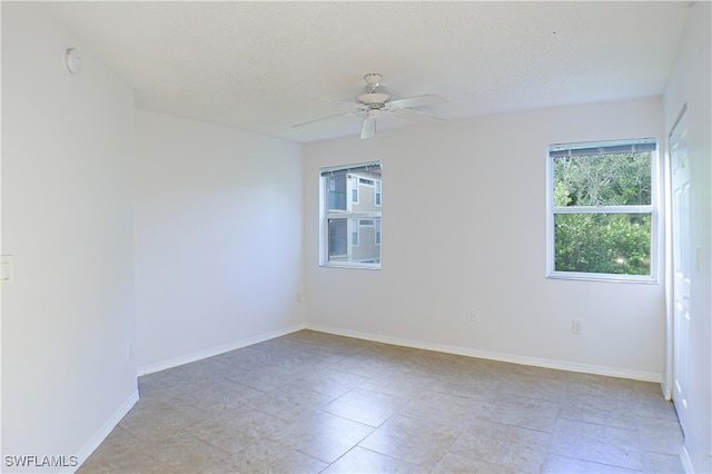 spare room featuring a textured ceiling, baseboards, and a ceiling fan