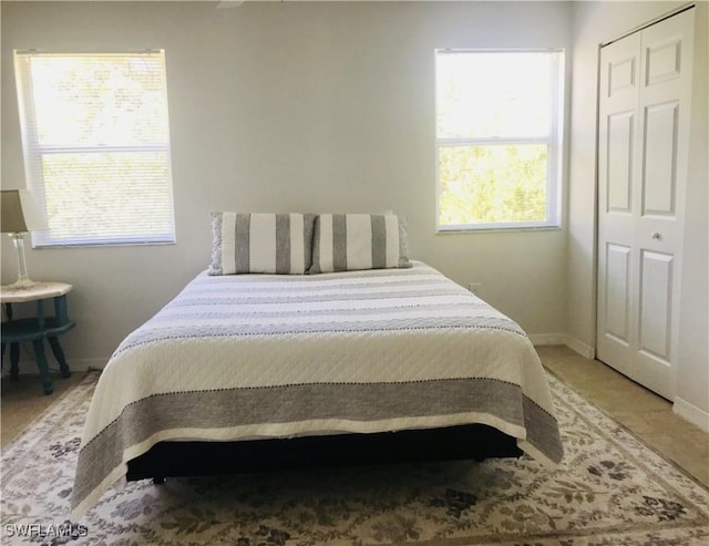 bedroom featuring a closet, baseboards, and light tile patterned floors