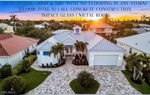 27080 Flamingo Dr, Bonita Springs, FL 34135 - view of front of property with a garage, cooling unit, decorative driveway, a standing seam roof, and metal roof