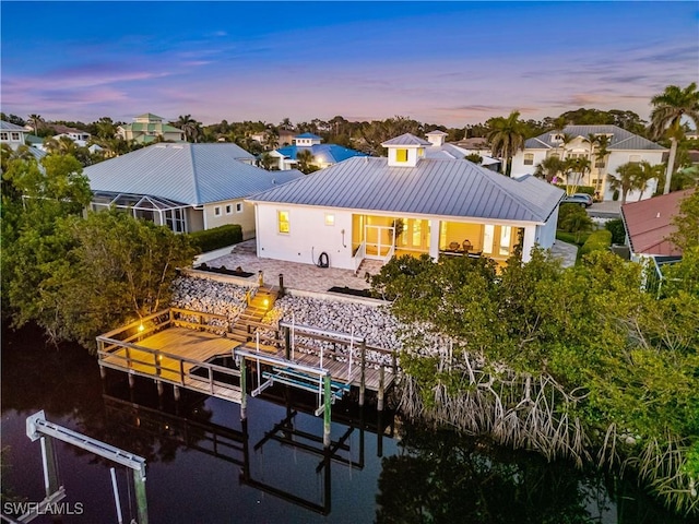 27080 Flamingo Dr, Bonita Springs, FL 34135 - back of house at dusk featuring boat lift and metal roof