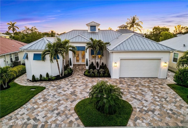 27080 Flamingo Dr, Bonita Springs, FL 34135 - view of front of house with central AC, a garage, a standing seam roof, decorative driveway, and french doors