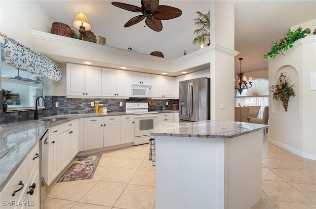 5131 SW 19th Ave, Cape Coral, FL 33914 - kitchen featuring tasteful backsplash, light tile patterned floors, a center island, appliances with stainless steel finishes, and ceiling fan with notable chandelier