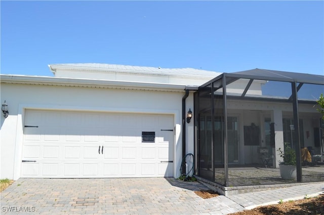 view of property exterior featuring an attached garage, a lanai, stucco siding, and driveway