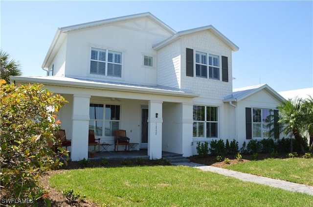 view of front of house featuring covered porch, a front yard, and stucco siding