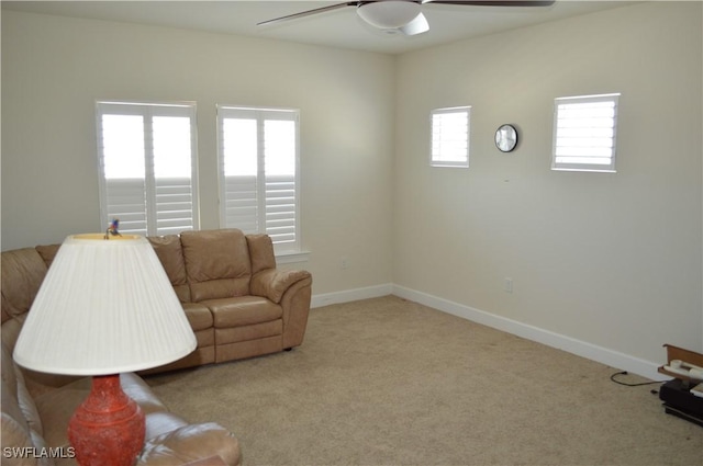 carpeted living area featuring baseboards and ceiling fan