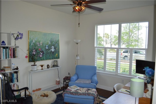 living area featuring wood finished floors, a ceiling fan, and baseboards