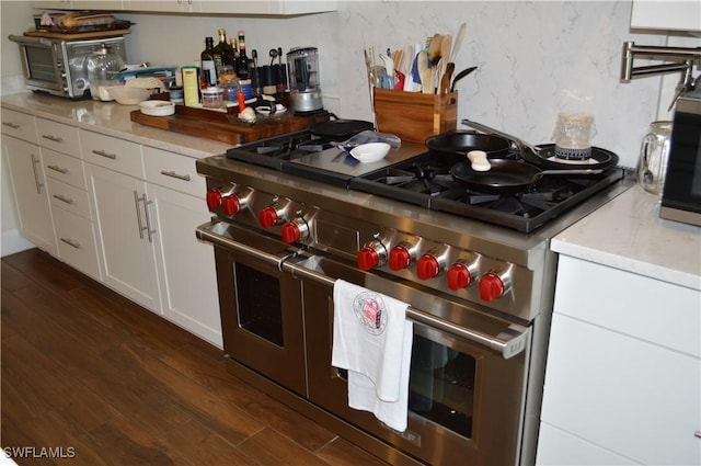 kitchen with a toaster, dark wood-style flooring, white cabinetry, light countertops, and appliances with stainless steel finishes