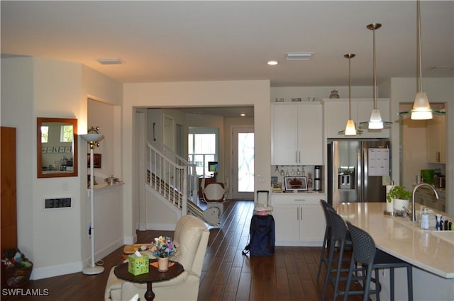 kitchen with light countertops, stainless steel fridge, white cabinetry, and dark wood-style flooring