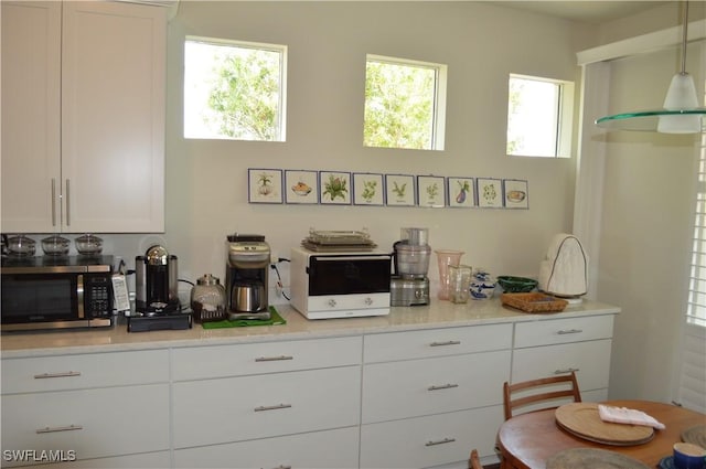 kitchen featuring stainless steel microwave, white cabinets, and light countertops