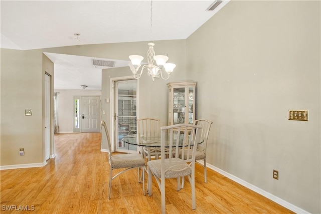 dining space with vaulted ceiling, a chandelier, baseboards, and light wood-style flooring