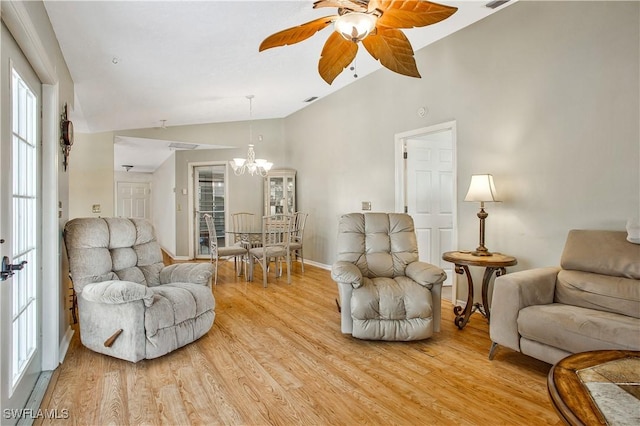 living area featuring vaulted ceiling, a chandelier, ceiling fan, light wood-type flooring, and baseboards