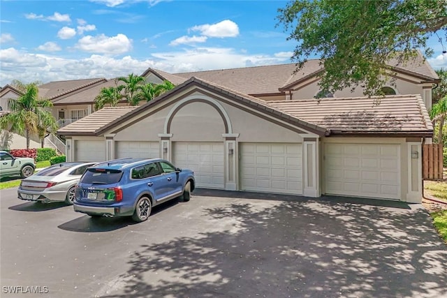 28750 Diamond Dr Unit 205, Bonita Springs, FL 34134 - view of front facade with a garage, stucco siding, driveway, and a tiled roof